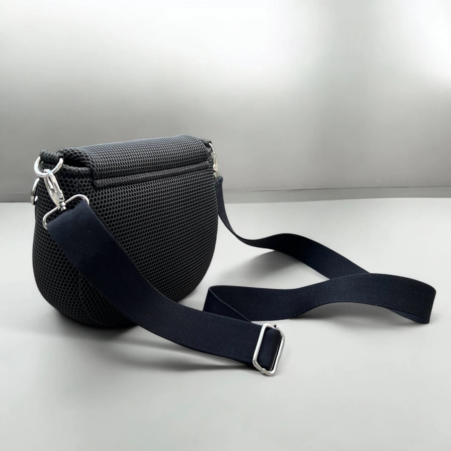 Halbrunde medium sized Gassitasche in Farbe schwarz aus Mesh Material mit schwarzen Tragegurt auf hellen Boden mit der Ansicht von hinten stehend