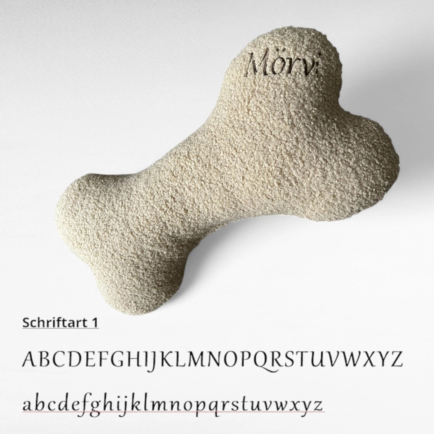 Kuscheliges Hundekissen in Knochenform aus Bouclestoff in beige mit brauner Namensstickerei Mörvi als Beispiel in Schriftart 1