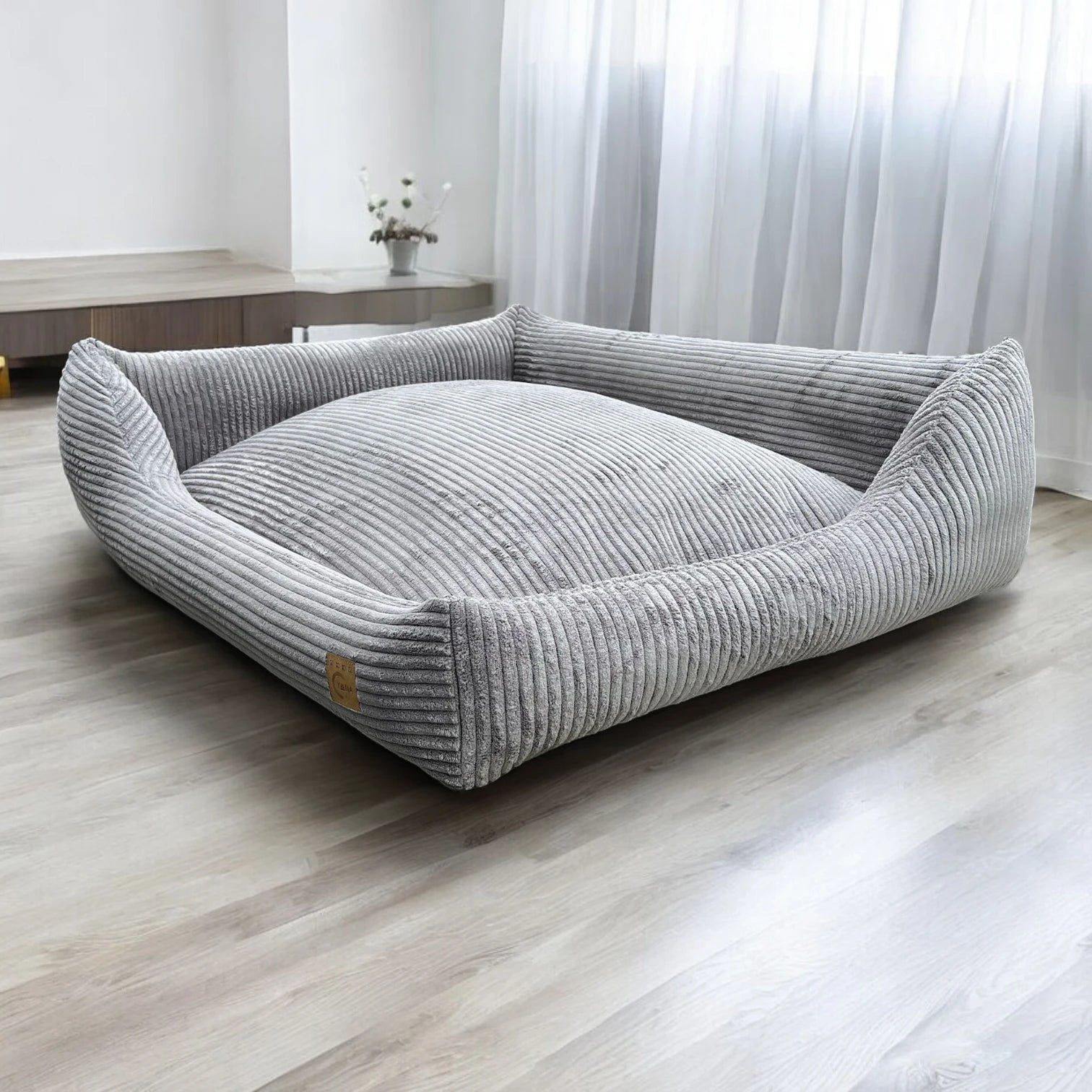 Schrägansicht rechteckiges Hundebett Gin mit asymmetrischem Polsterrand aus grauem Breitcord Stoff in hellem Zimmer