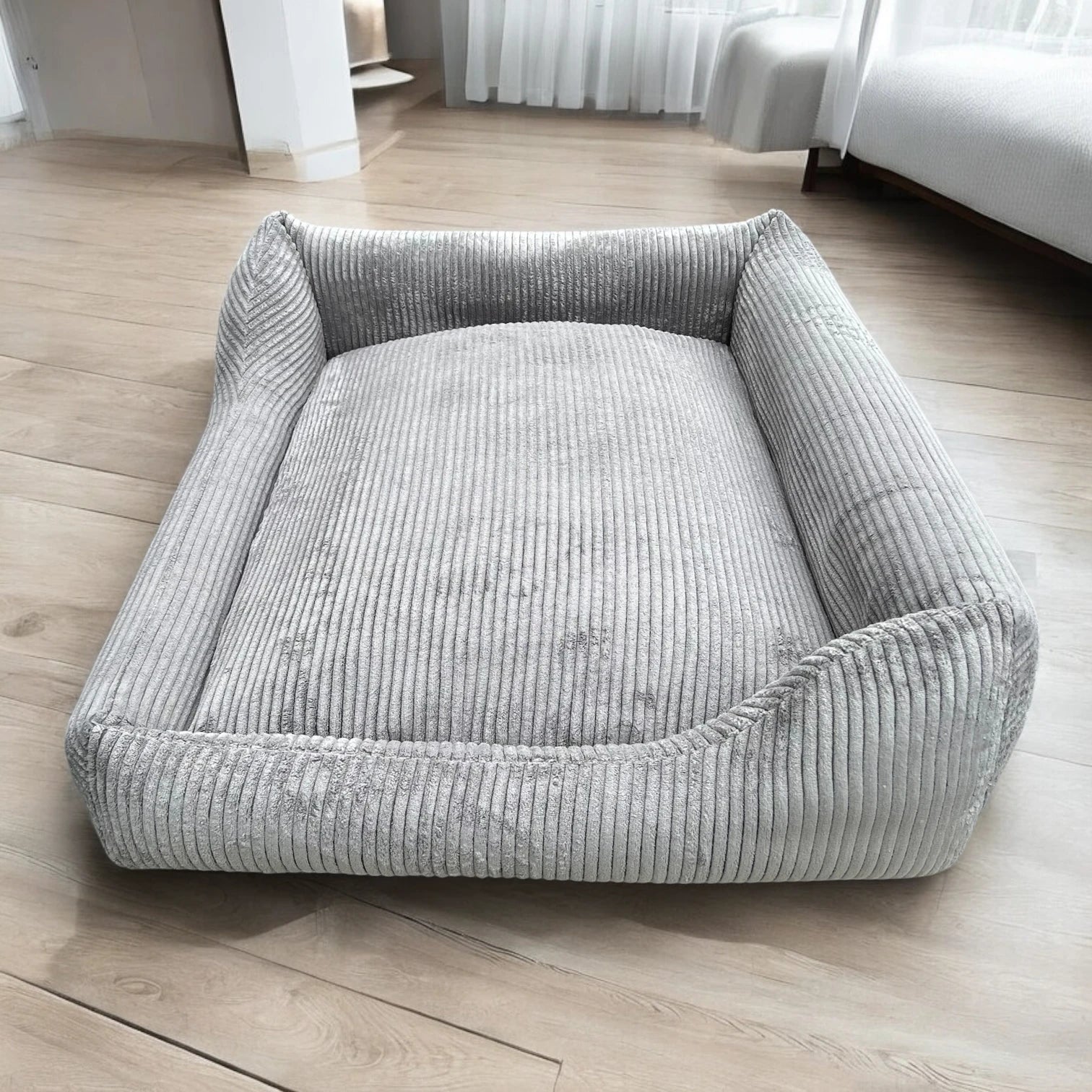 Seitenansicht rechteckiges Hundebett Gin mit asymmetrischem Polsterrand aus grauem Breitcord Stoff in hellem Zimmer