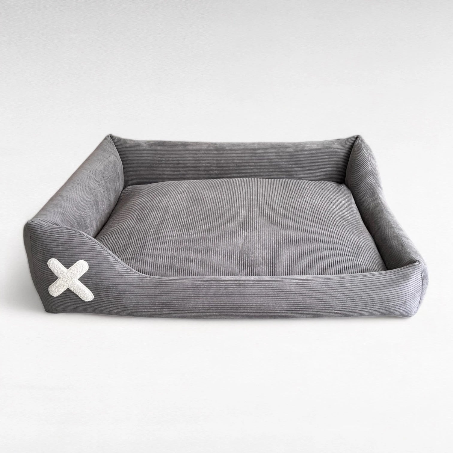 Rechteckiges Hundebett mit asymmetrischen Seitenpolstern und dunkelgrauem Cordbezug und Plüschapplikation in Kreuzform