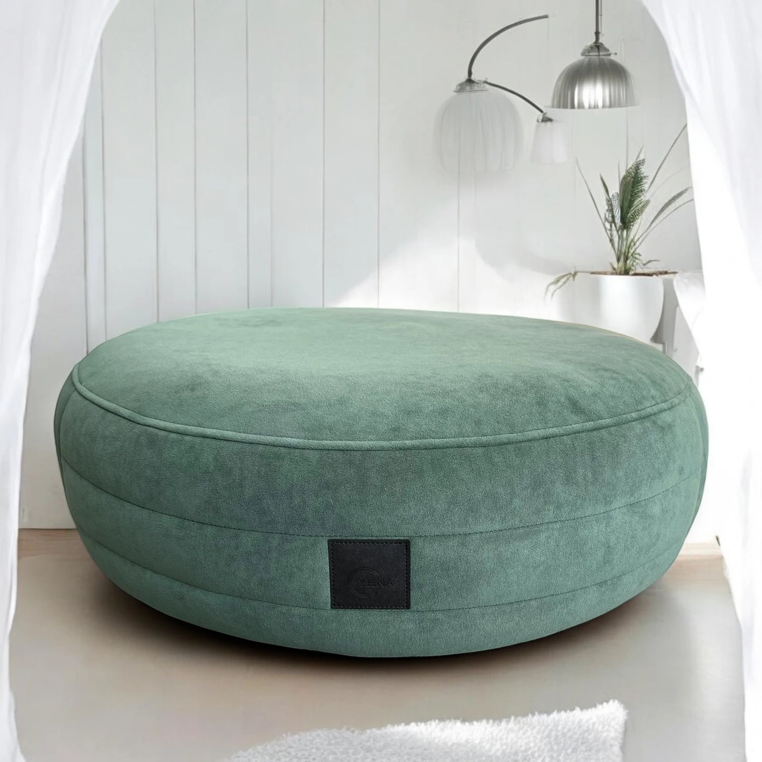 Smaragdgrünes rundes Hundebett Yumi mit rundherum laufenden Steppungen uns schwarzem Yuna Label mit minimalistischem Hintergrund