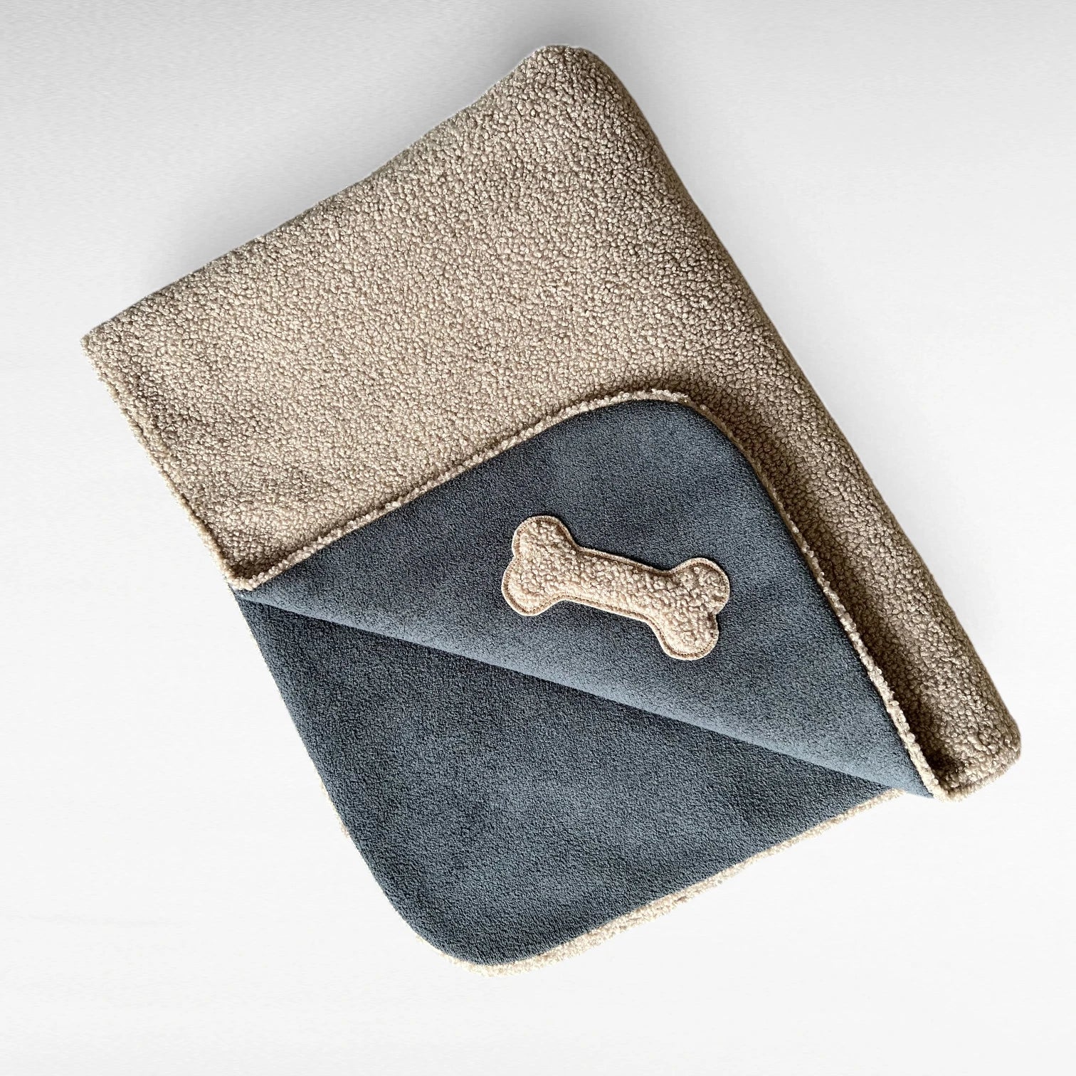 Gefaltete Hundedecke in Farbe Anthrazit taupe mit beidseitiger Ansicht sowie knochenförmiger Teddyapplikation in Farbe taupe
