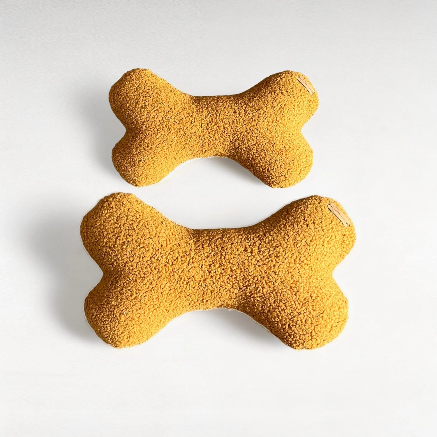 2 Hundekissen in Knochenform aus Boucléstoff in safran