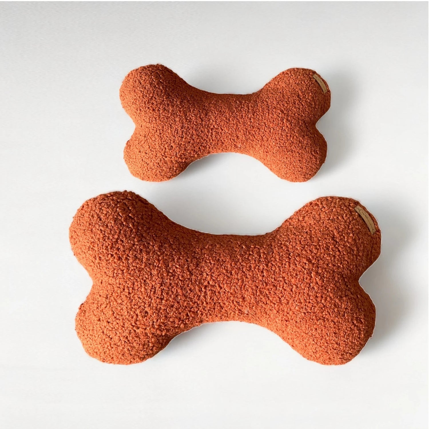 2 Hundekissen in Knochenform aus Boucléstoff in terracotta