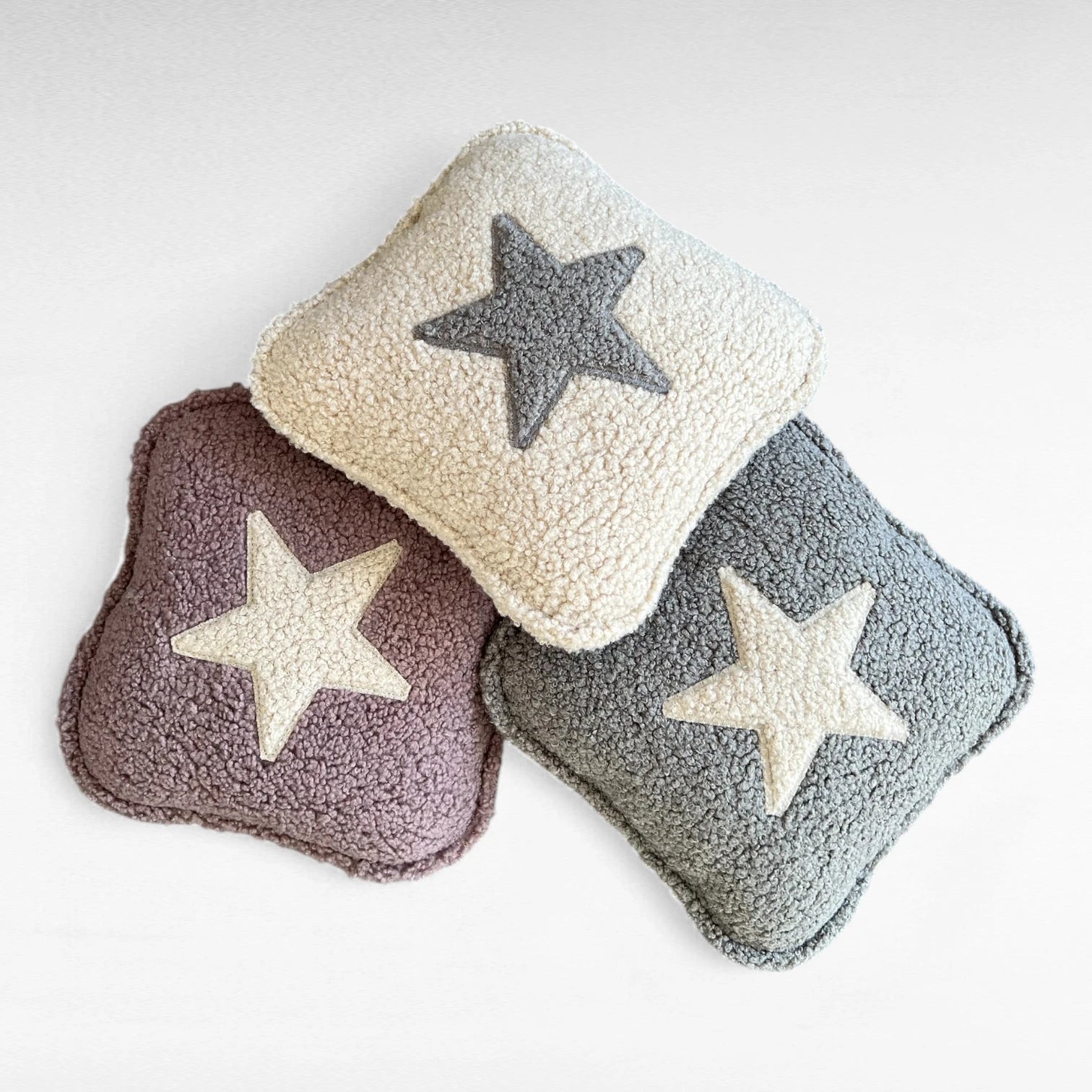 3 quadratische Kissen aus Boucle in beige, altrosa und grau jeweils mit Stern Applikation