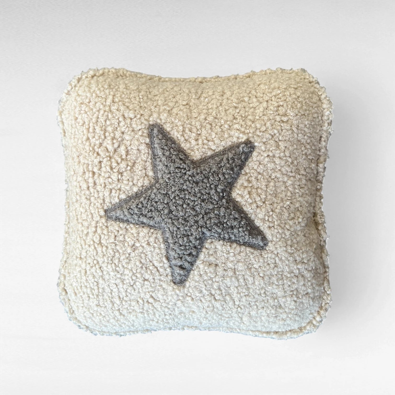 Quadratisches Kissen aus Bouclestoff in beige mit Stern Applikation grau