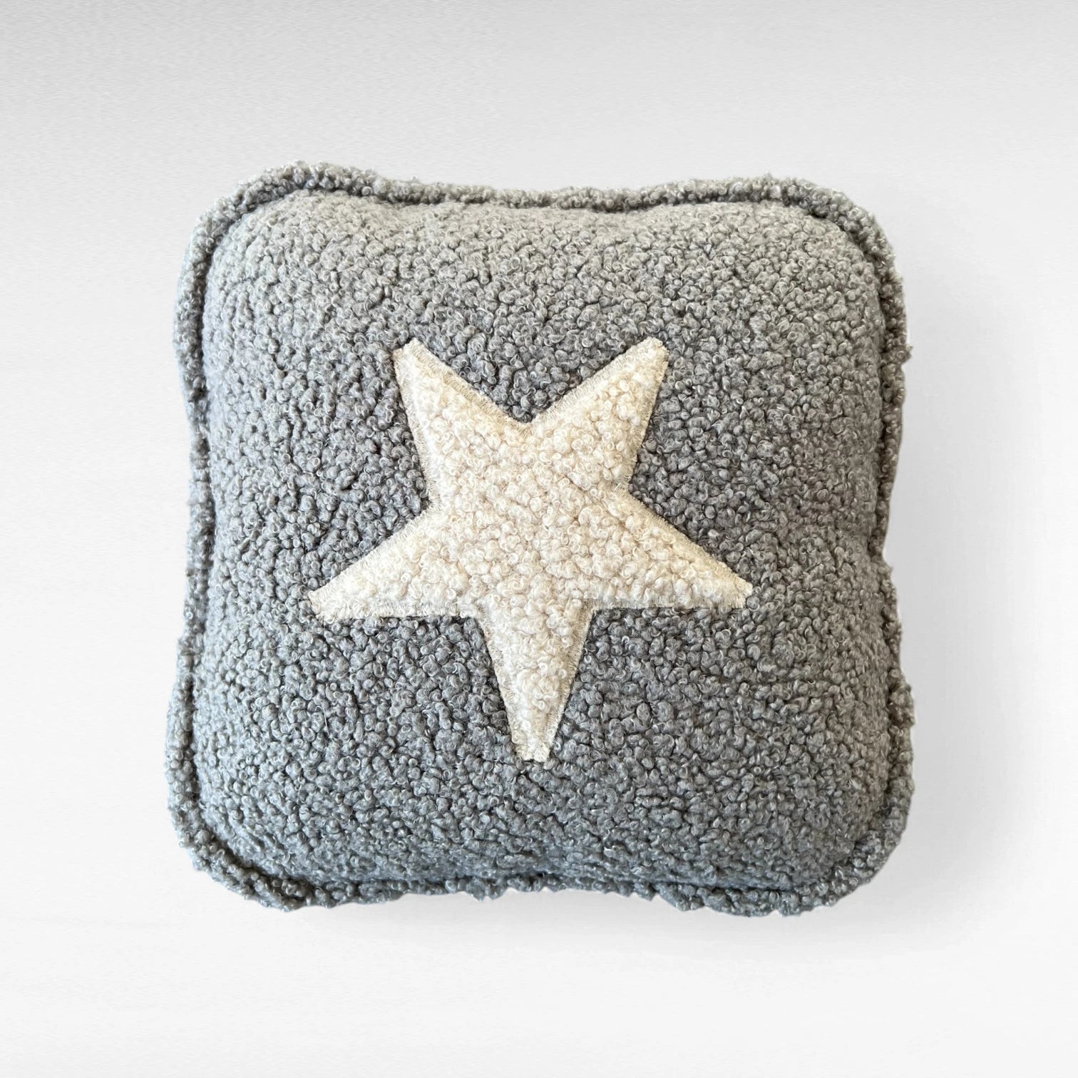 Quadratisches Kissen aus Bouclestoff in grau mit Stern Applikation beige