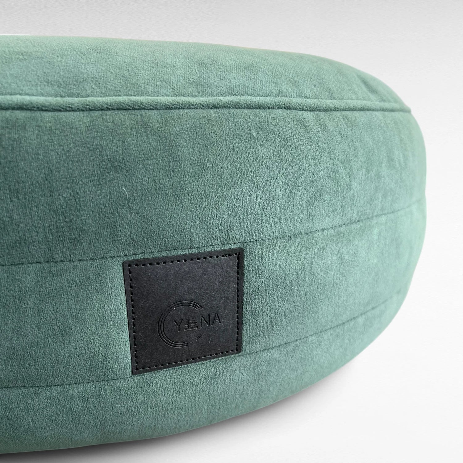 Nahaufnahme smaragdgrünes rundes Hundebett Yumi mit rundherum laufenden Steppungen uns schwarzem Yuna Label