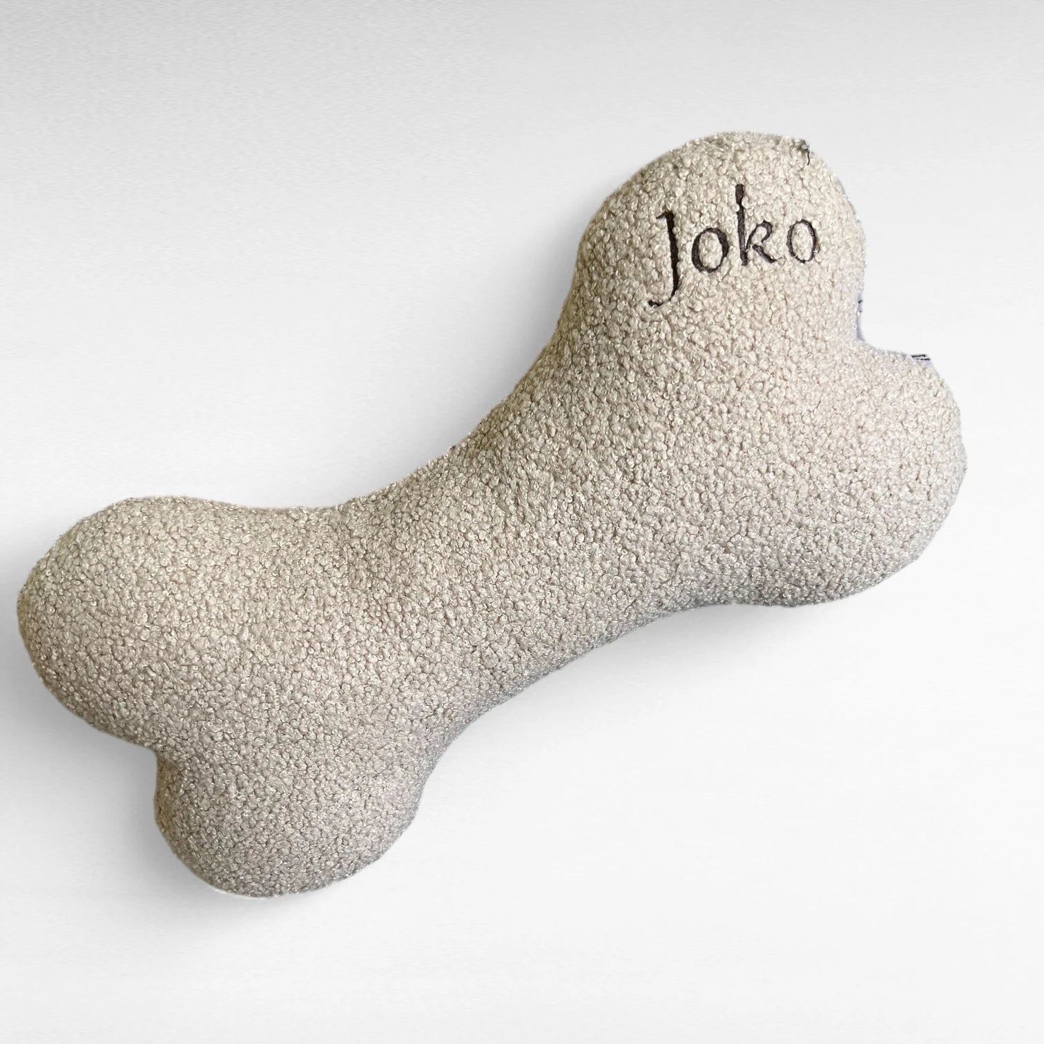 Beiges Hundekissen in Knochenform aus Bouclestoff beige mit Stickerei Joko