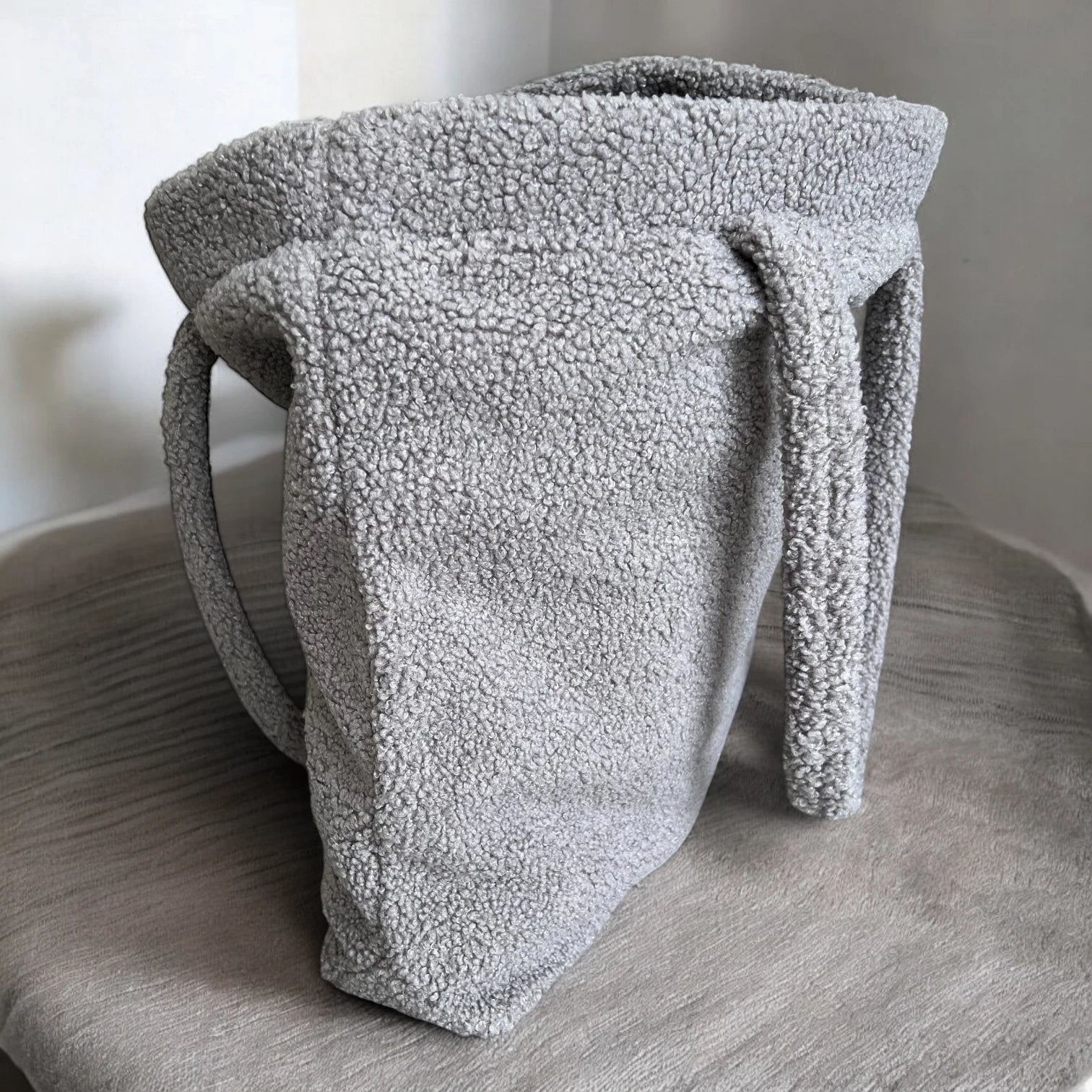 Rechteckiger Shopper aus Teddyfell in Farbe grau stehend und halb geöffnet mit minimalistischem Hintergrund