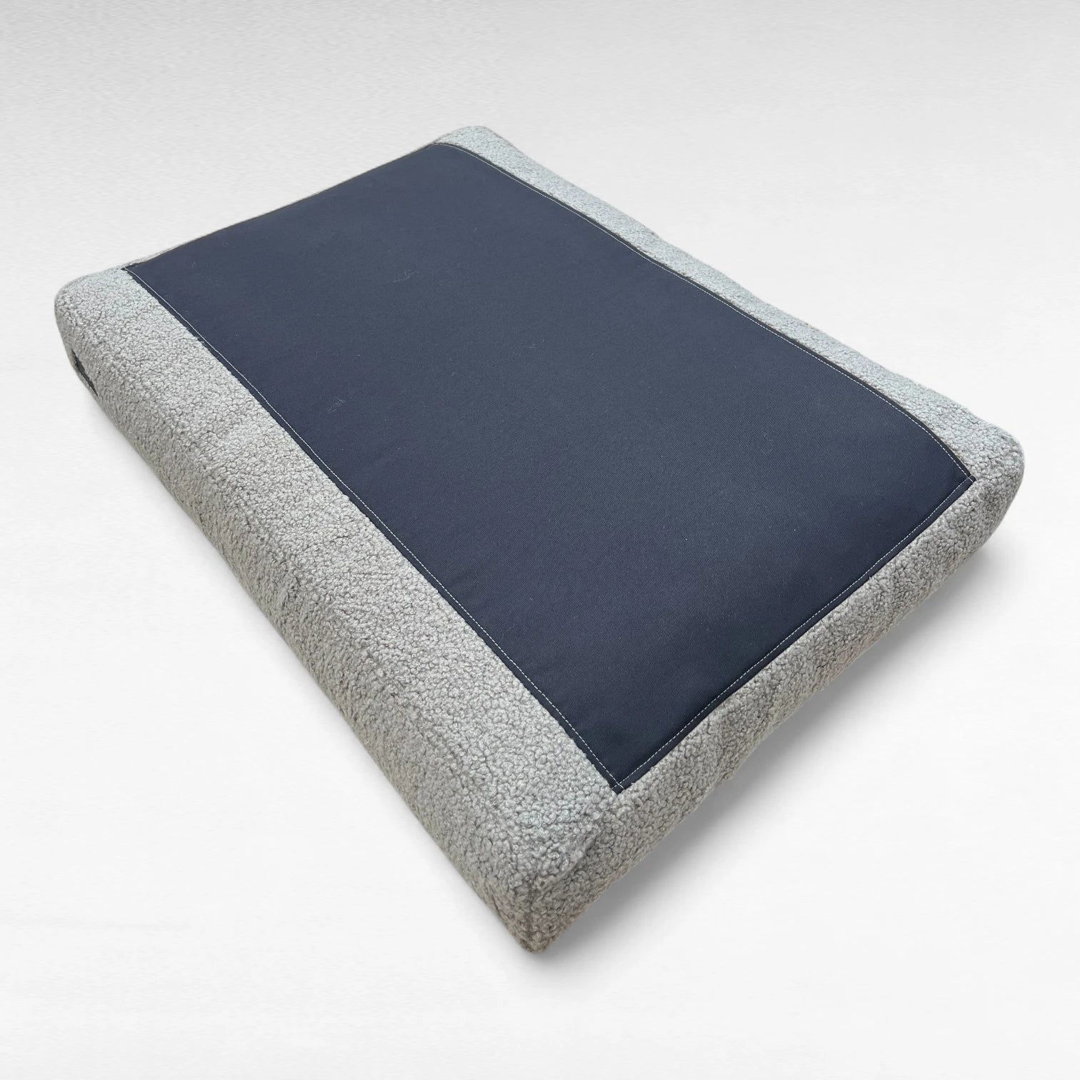 Bodenansicht rechteckiges Hundekissen mit grauem Bouclebezug und schwarzem Bodenmaterial