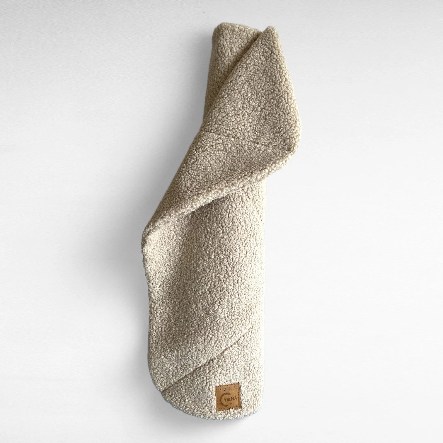 Beige rechteckige Hundedecke mit abgerundeten Ecke und Ziersteppungen aus hochwertigem Boucle-Stoff gerollt