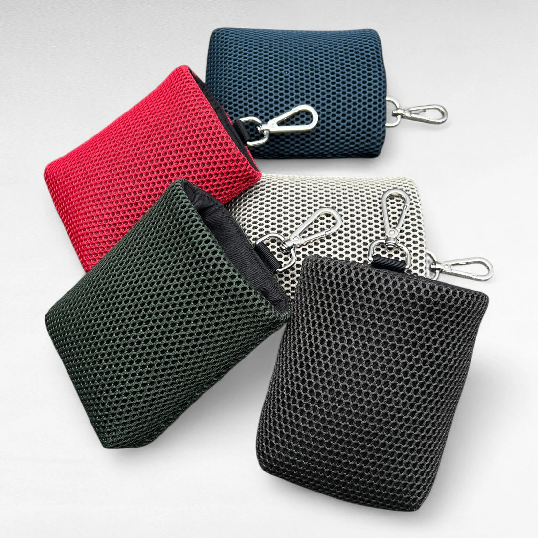 Fünf rechteckige Leckeribeutel mit Metallkarabiner aus Mesh Material in den  Farben blau, rot, beige, dunkelgrün, schwarz von oben nach unten im Bild