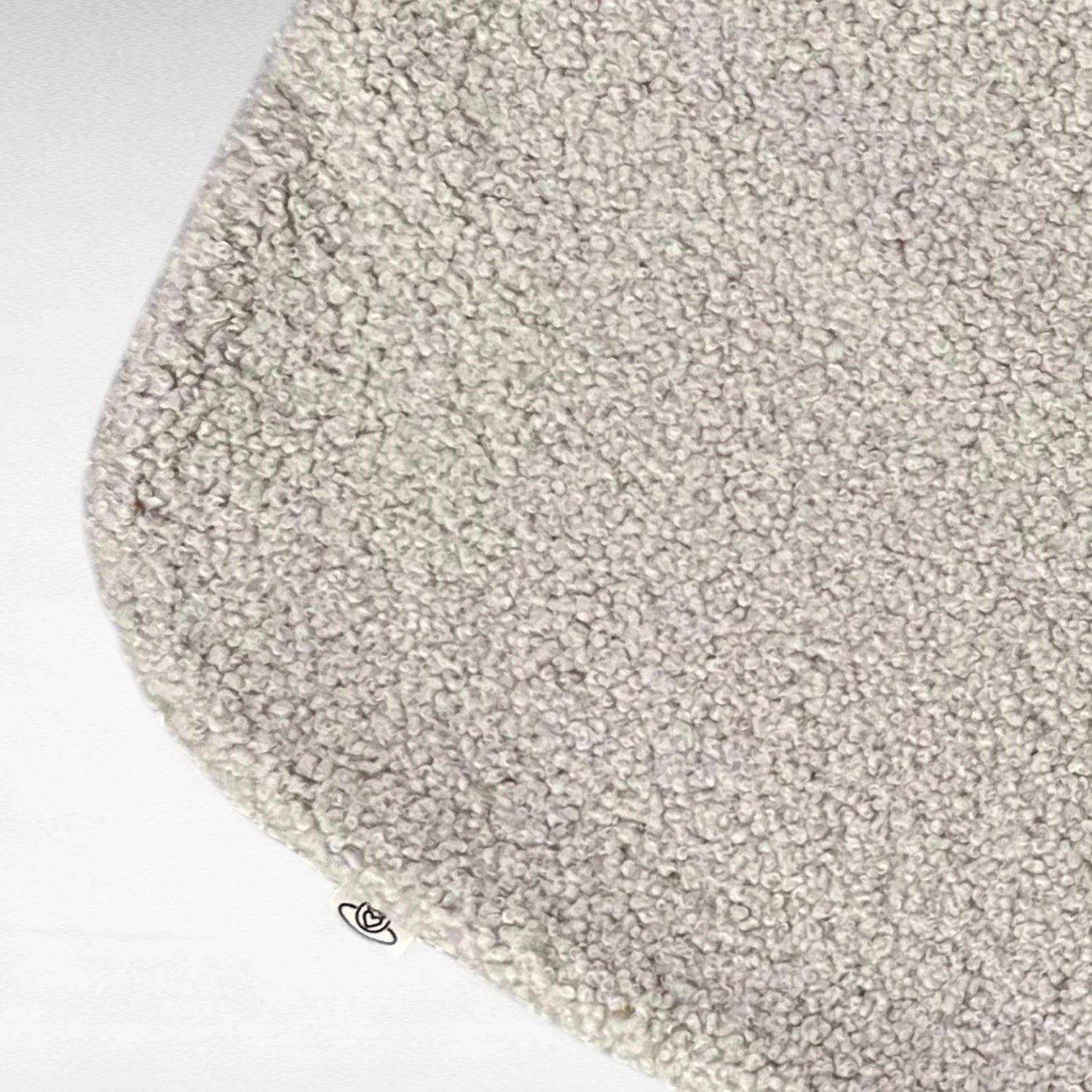 Nahaufnahme von kuscheliger rechteckeiger minimalistischer Hundedecke mit abgerundeten Kanten aus hochwertigem Boucle Stoff in Farbe beige