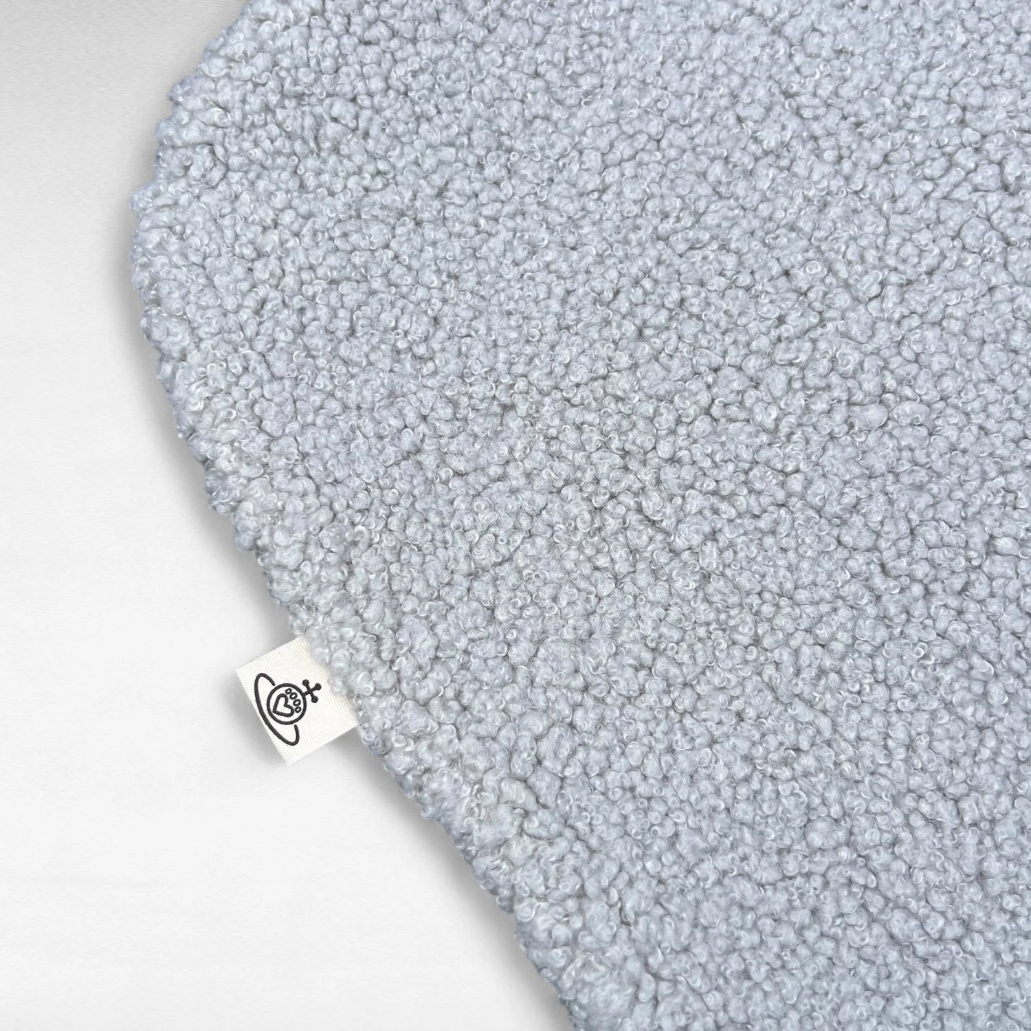 Nahaufnahme Hundedecke aus flauschigem Bouclé Stoff mit abgerundeten Kanten in hellgrau und ogoetikett