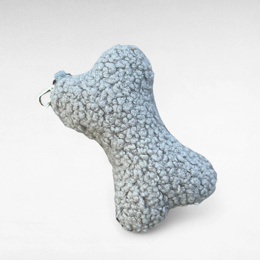 Knochenförmiges kleines Boucle-Kissen mit Karabinerhaken als Taschenanhänger in Farbe hellgrau
