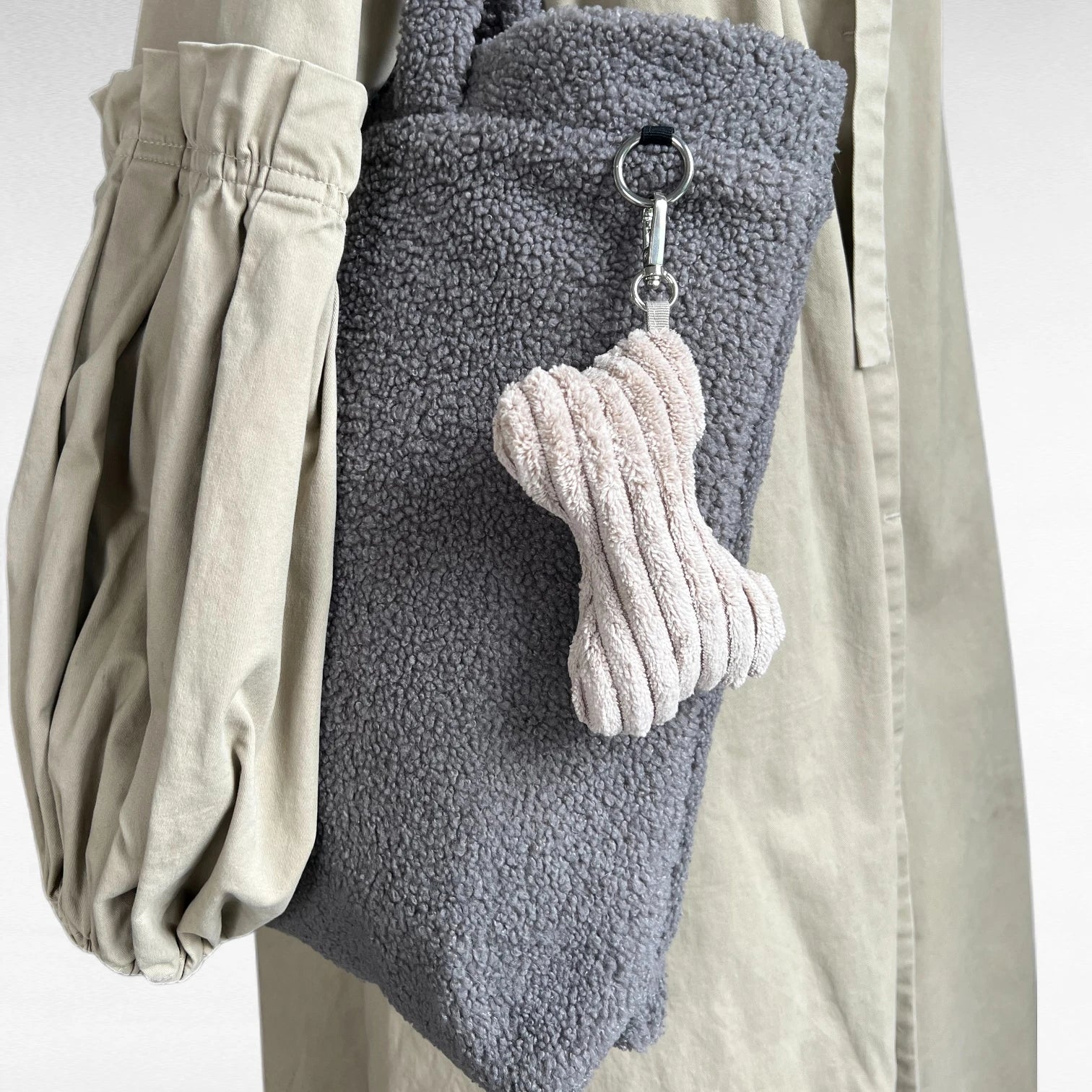 Deko Taschenanhänger in Knochenform aus beigem Breitcord mit kleinem Karabiner an Teddy Shopper in grau hängend
