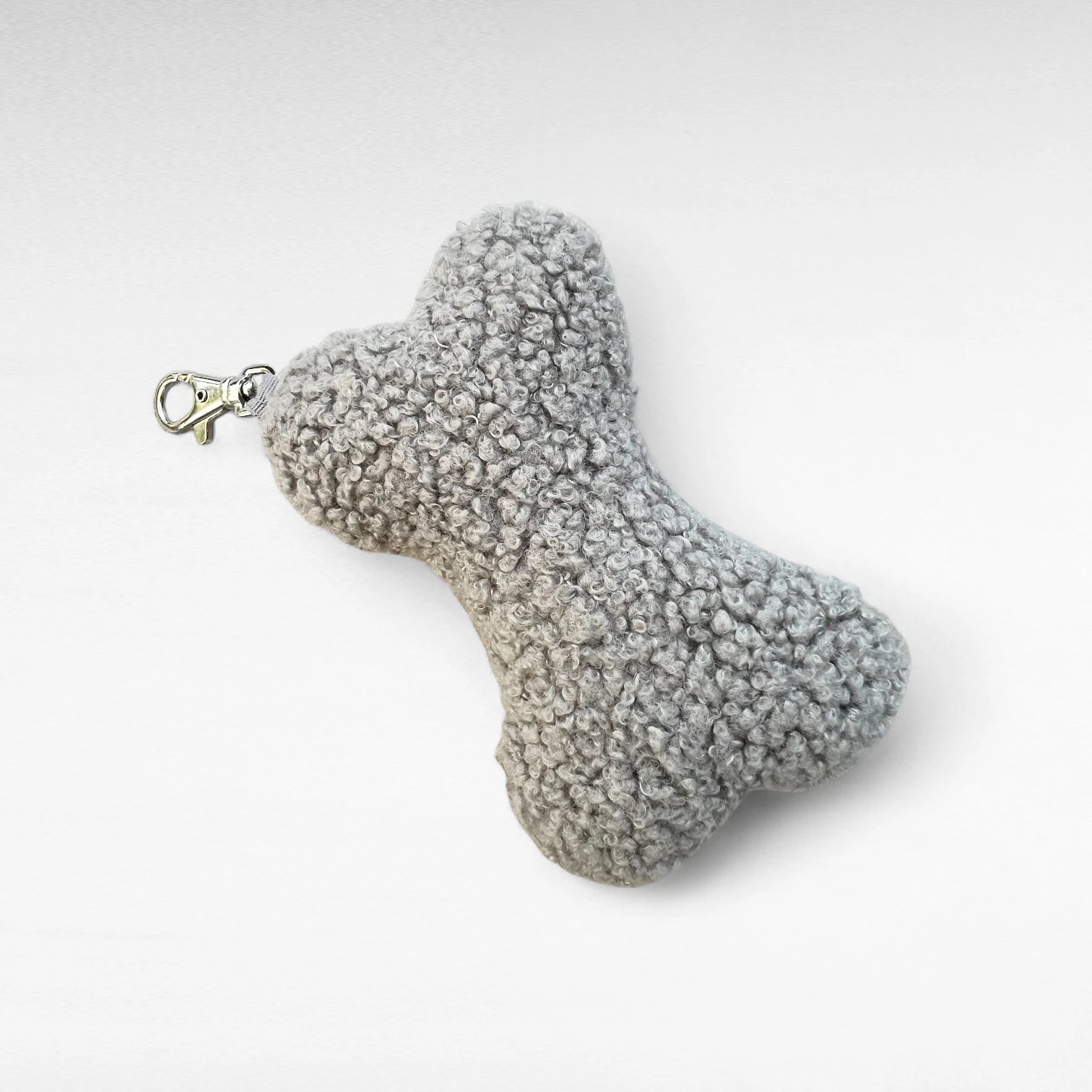 Knochenförmiges kleines Boucle-Kissen mit Karabinerhaken als Taschenanhänger in Farbe grau