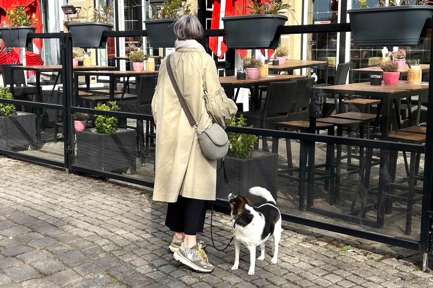 Frau trägt halbrunde Gassitasche in Farbe beige mit dabei ein kleiner schwarz weißer Hund