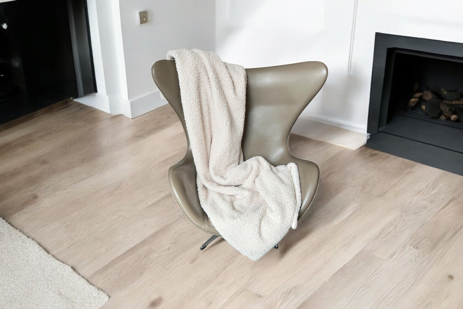 Cremefarbene Kuscheldecke über Egg Chair drapiert