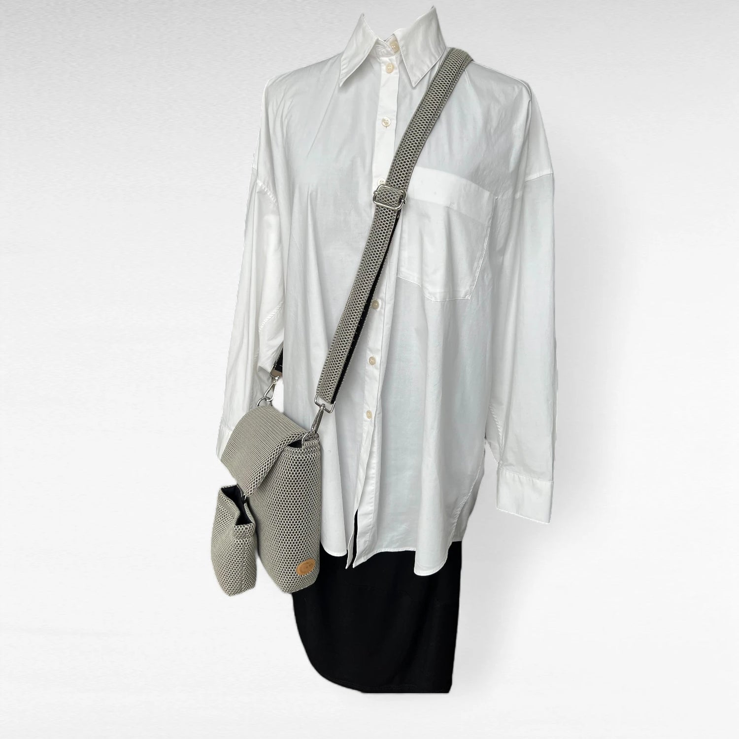 Rechteckige Gassitasche inklusive Leckerlibeutel aus Mesh Material in beige und silberfarbenen Metallelemente über Schneiderpuppe mit weißem Hemd hängend