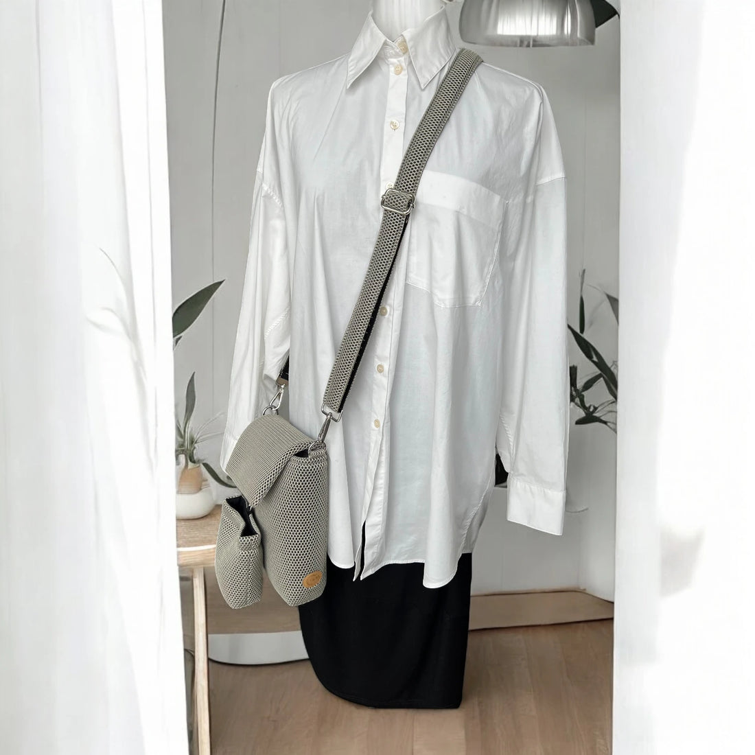Rechteckige Gassitasche inklusive Leckerlibeutel aus Mesh Material in beige und silberfarbenen Metallelemente über Schneiderpuppe mit weißem Hemd hängend