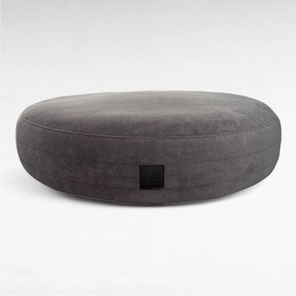 Dunkelgraues rundes Hundebett Yumi mit rundherum laufenden Steppungen uns schwarzem Yuna Label 