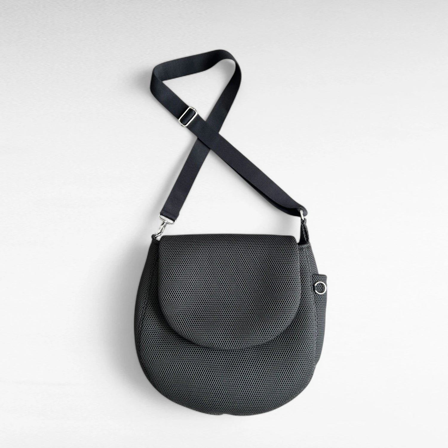 Runde oversized -Tasche mit Taschenklappe aus schwarzem Mesh Material mit schwarzem Gurt und Metallelemente in silber