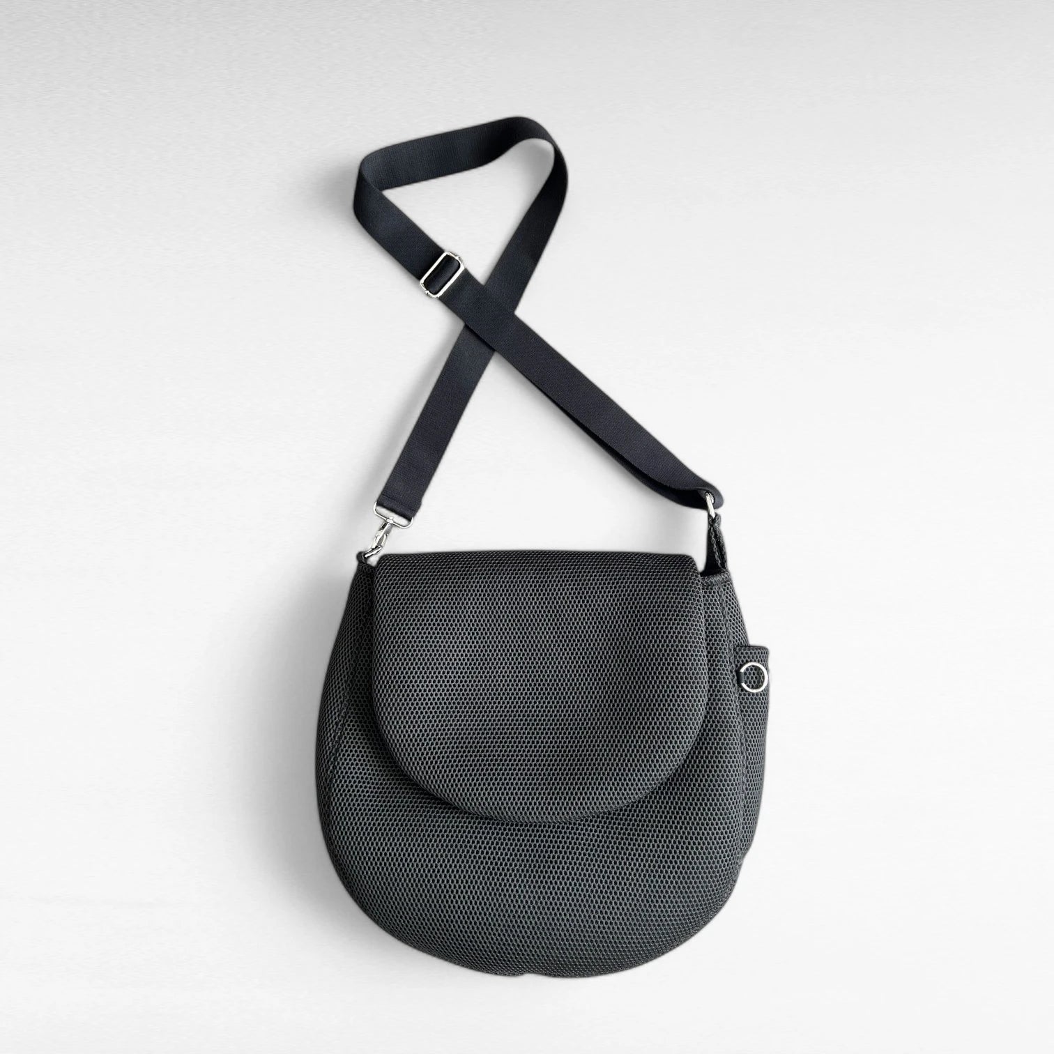 Runde oversized -Tasche mit Taschenklappe aus schwarzem Mesh Material mit schwarzem Gurt und Metallelemente in silber