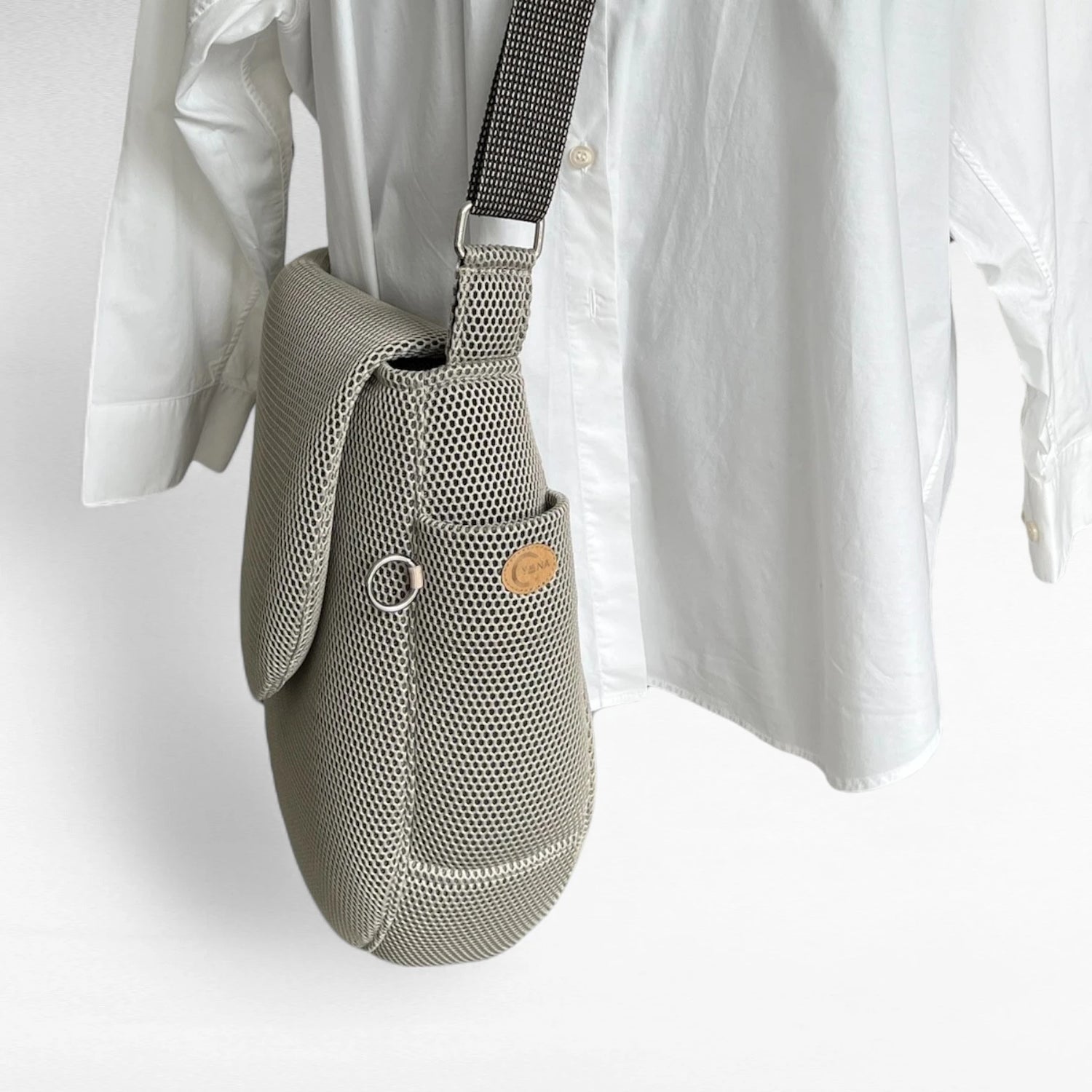 Seitenansicht oversized Tasche in runder Form aus beigem Mesh Material mit Yuna Logo natur und Metallring silberfarben