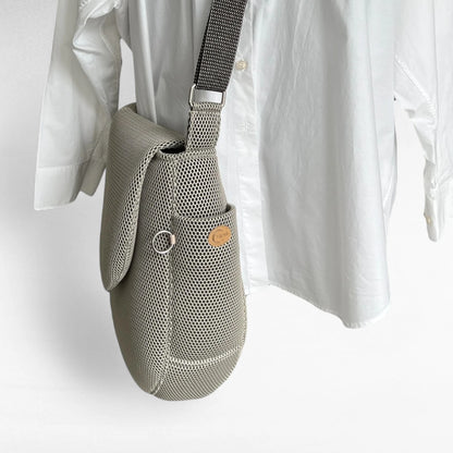 Seitenansicht oversized Tasche in runder Form aus beigem Mesh Material mit Yuna Logo natur und Metallring silberfarben