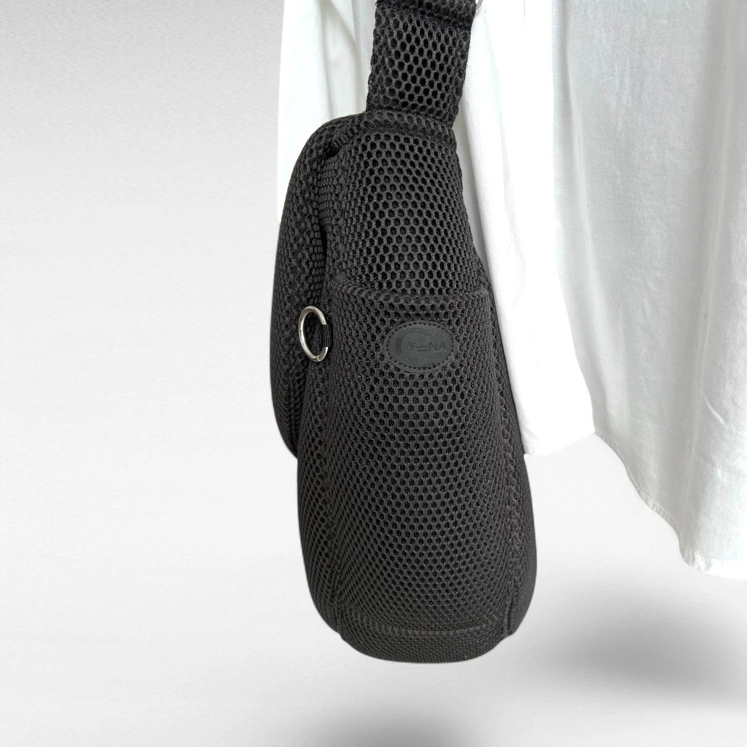 Seitenansicht oversized Tasche in runder Form aus schwarzem Mesh Material mit Yuna Logo schwarz und Metallring silberfarben