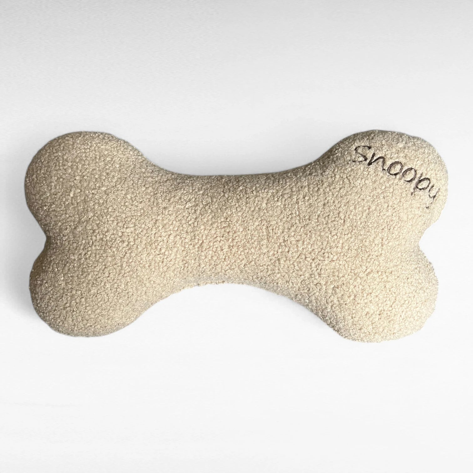 Beiges Hundekissen in Knochenform aus Bouclestoff beige mit Stickerei Snoopy
