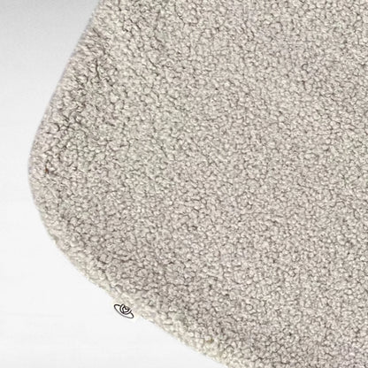 Nahaufnahme von kuscheliger rechteckeiger minimalistischer Hundedecke mit abgerundeten Kanten aus hochwertigem Boucle Stoff in Farbe beige 