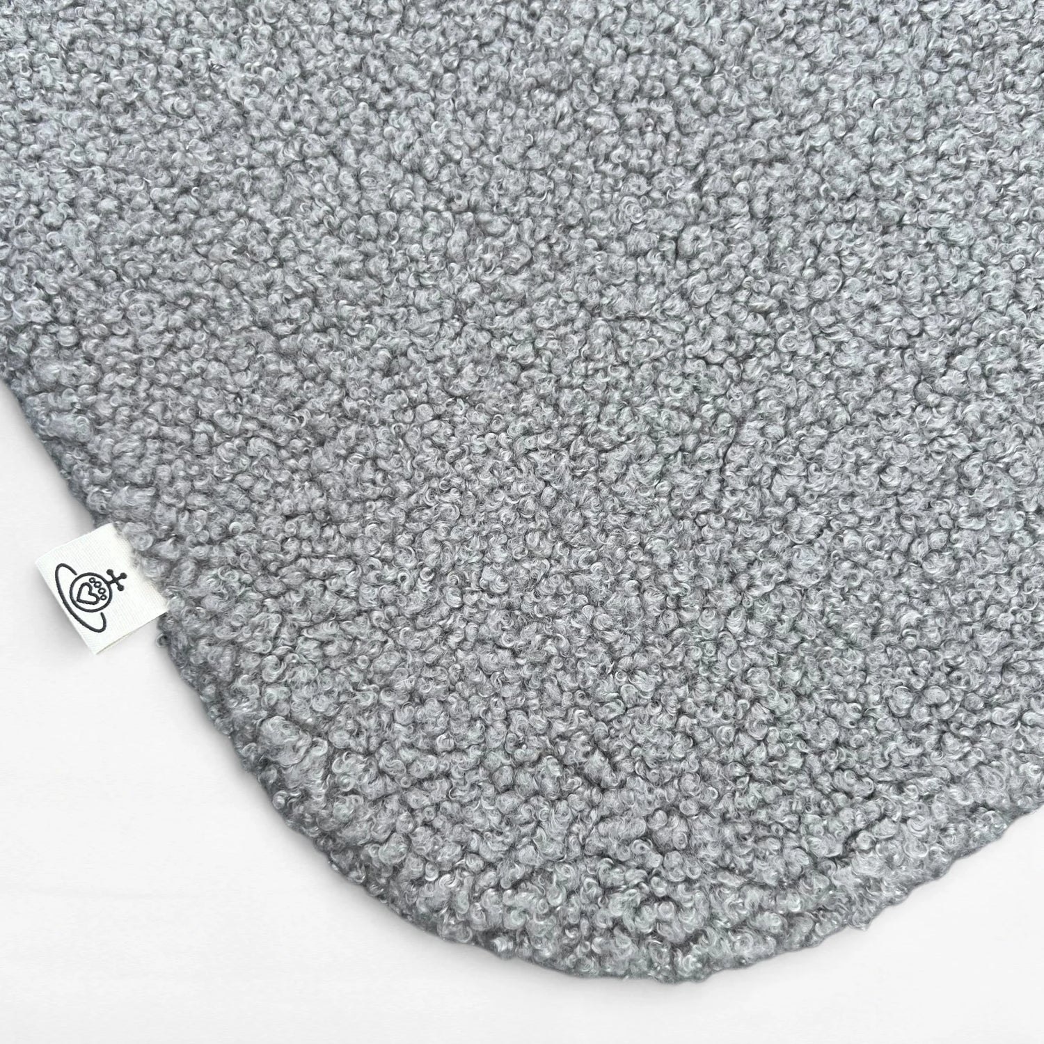 Nahaufnahme Hundedecke aus flauschigem Bouclé Stoff mit abgerundeten Kanten in grau und Logoetikett