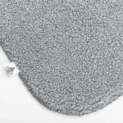 Nahaufnahme Hundedecke aus flauschigem Bouclé Stoff mit abgerundeten Kanten in grau und Logoetikett